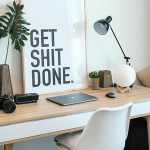 Mini SEO audit - desk with white chair, framed "Get Shit Done" print leaning against the wall, lamp, keyboard, stationary and plant