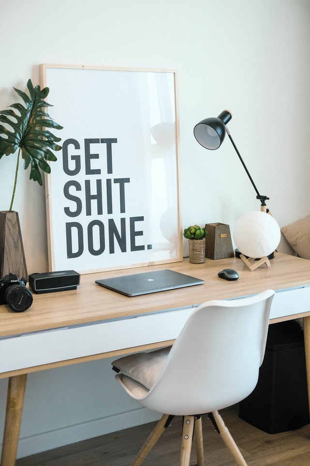 Mini SEO audit - desk with white chair, framed "Get Shit Done" print leaning against the wall, lamp, keyboard, stationary and plant
