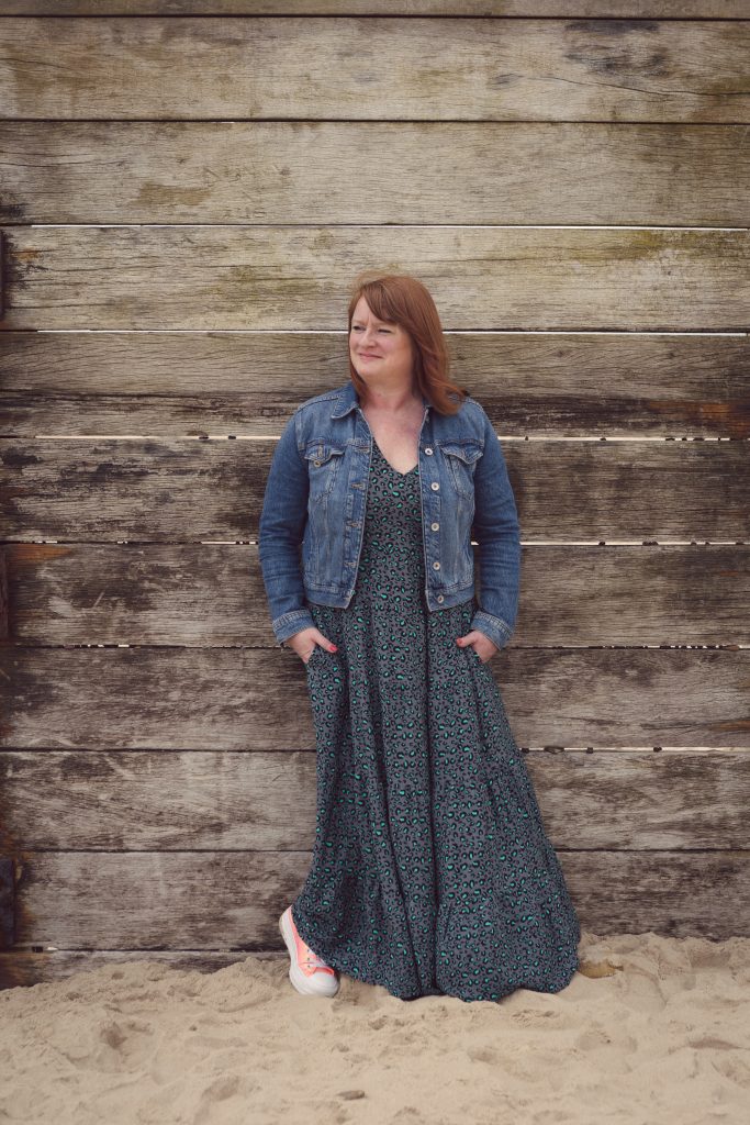 Suzy Stanton standing on a beach against a wooden pier