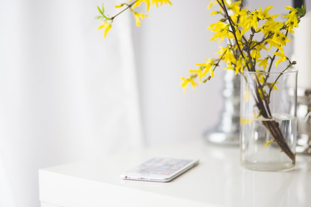 The best business kit represented by a smart phone on a white table next to a vase of yellow flowers