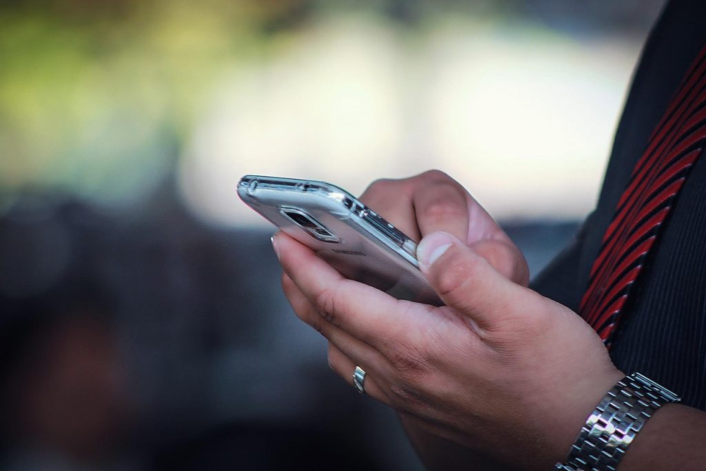 A pair of hands holding a mobile phone with one finger on the screen