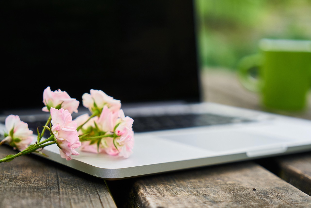 An open laptop with pink flowers on the keyboard