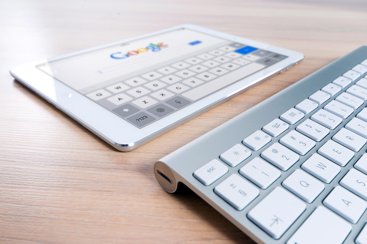 A keyboard and white tablet displaying Google search screen to show small business SEO glow-up 