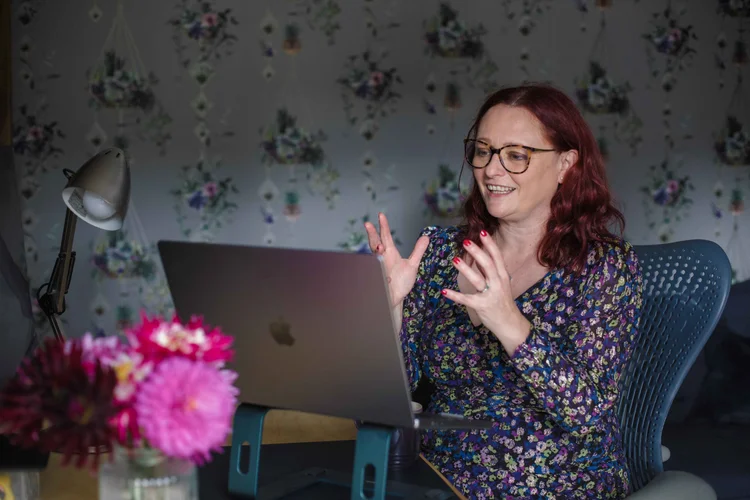 The Career Happiness coach Jenny Holliday delivering a coaching session via her laptop against a backdrop of floral wallpaper.